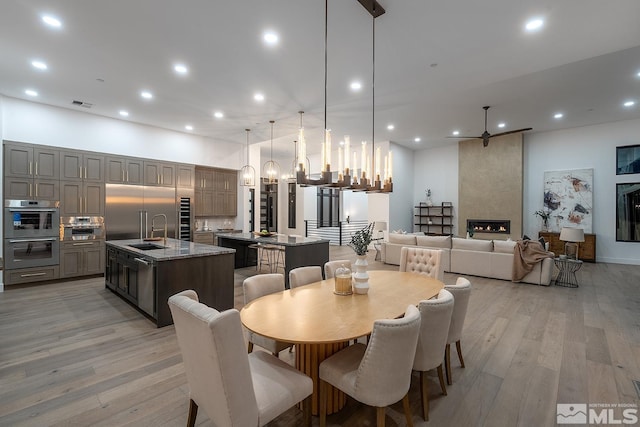 dining space with an inviting chandelier, light hardwood / wood-style flooring, a fireplace, and sink