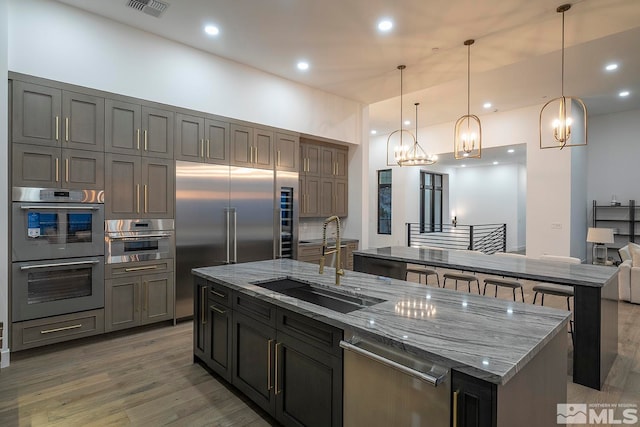 kitchen featuring hanging light fixtures, sink, a large island with sink, a chandelier, and appliances with stainless steel finishes