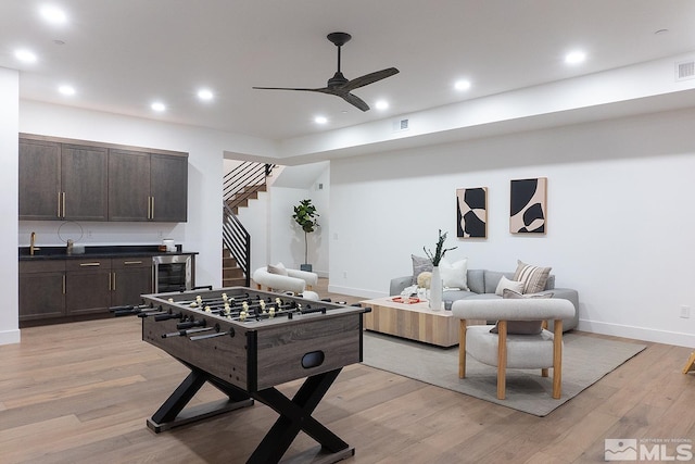 game room with ceiling fan, wine cooler, and light wood-type flooring