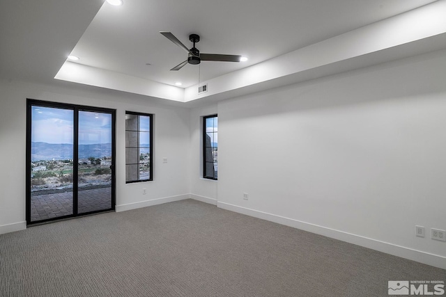 spare room featuring carpet flooring, a tray ceiling, and ceiling fan