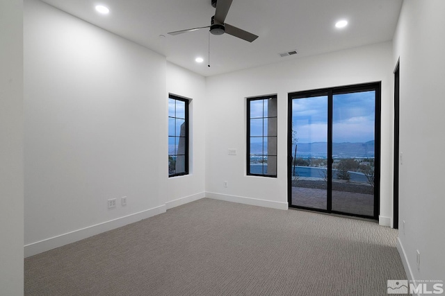 spare room featuring light carpet, ceiling fan, and a mountain view