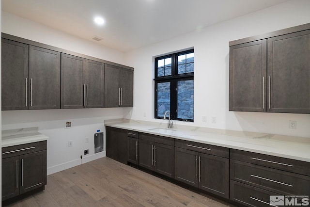 kitchen featuring dark brown cabinets, light wood-type flooring, and sink