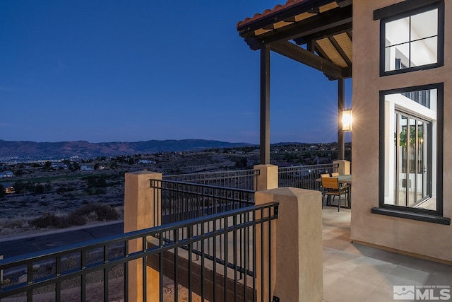 balcony at dusk with a patio and a mountain view