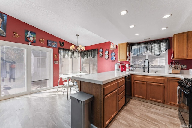 kitchen featuring a wealth of natural light, black appliances, kitchen peninsula, and decorative light fixtures