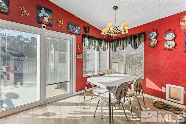 dining room featuring an inviting chandelier, hardwood / wood-style floors, vaulted ceiling, and a textured ceiling