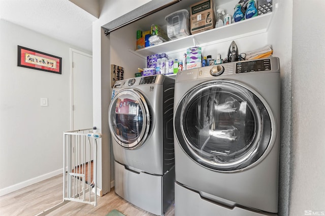 laundry area with washing machine and clothes dryer, a textured ceiling, and light hardwood / wood-style flooring