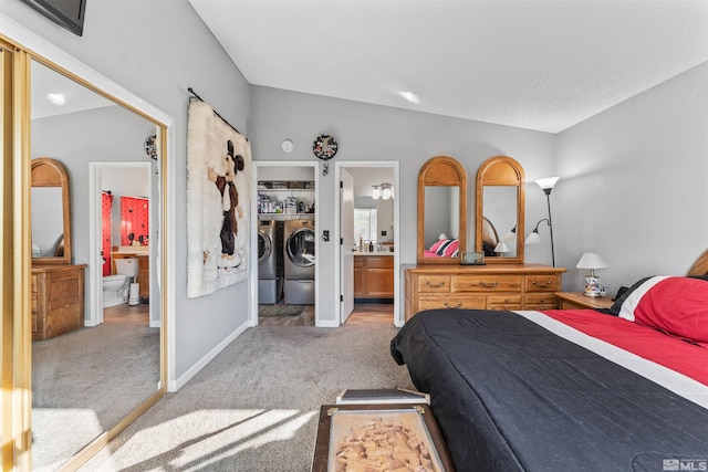 bedroom featuring carpet floors, vaulted ceiling, washer and dryer, and ensuite bathroom