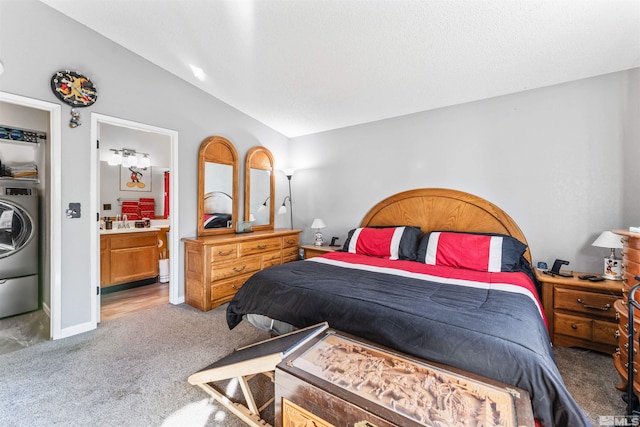 bedroom with lofted ceiling, carpet flooring, ensuite bath, and washer / dryer