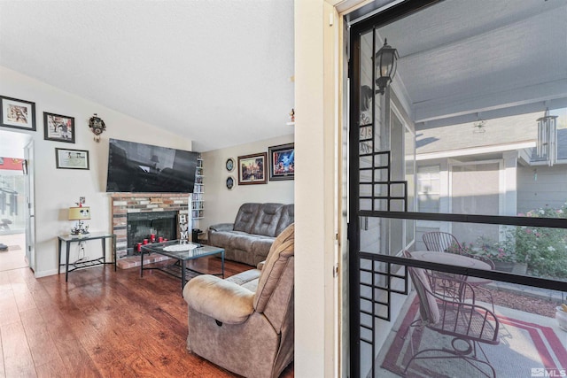 living room featuring hardwood / wood-style flooring, a fireplace, vaulted ceiling, and a healthy amount of sunlight