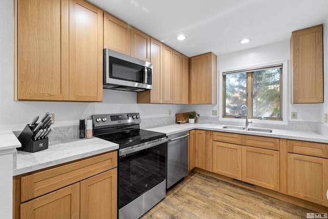 kitchen with sink, light hardwood / wood-style flooring, light brown cabinets, appliances with stainless steel finishes, and light stone countertops