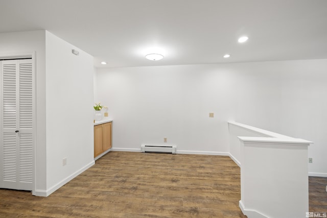 spare room featuring baseboard heating and dark wood-type flooring