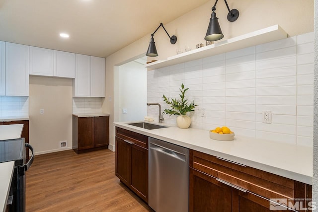 kitchen with hanging light fixtures, sink, tasteful backsplash, dishwasher, and light wood-type flooring