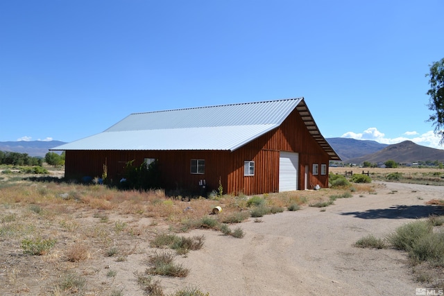 view of property exterior featuring a garage, a mountain view, and an outbuilding