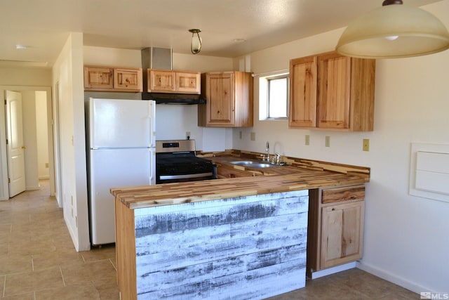 kitchen featuring butcher block counters, stainless steel range, white fridge, and sink