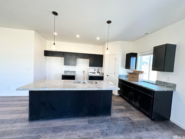 kitchen featuring dark hardwood / wood-style flooring, sink, pendant lighting, and a center island with sink