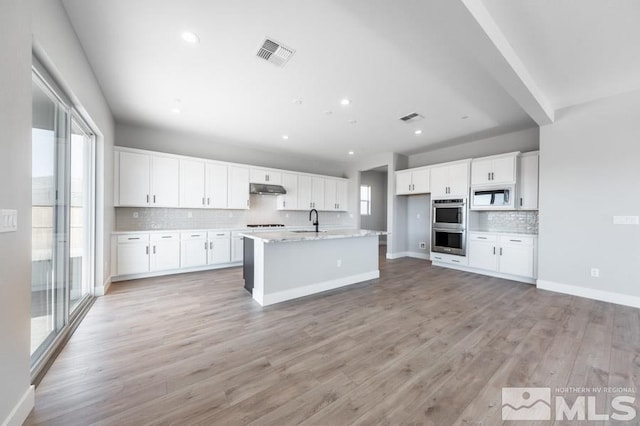 kitchen featuring white cabinets, light hardwood / wood-style floors, sink, and white microwave