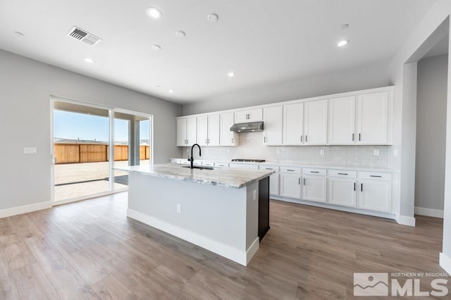 kitchen featuring a kitchen island with sink, sink, white cabinets, and light hardwood / wood-style floors