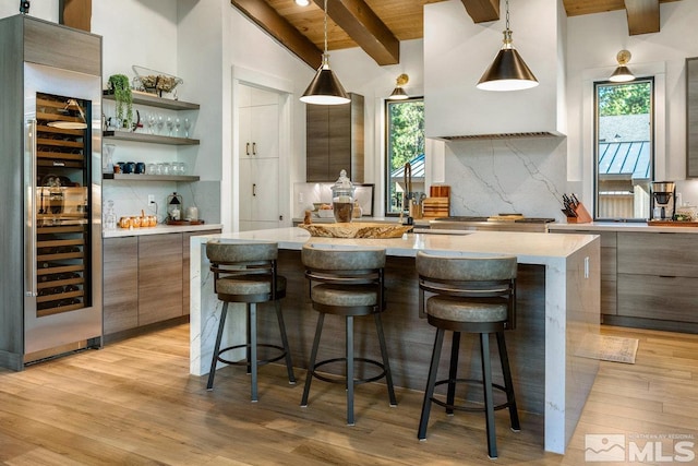 kitchen with wood ceiling, light hardwood / wood-style floors, beverage cooler, hanging light fixtures, and decorative backsplash