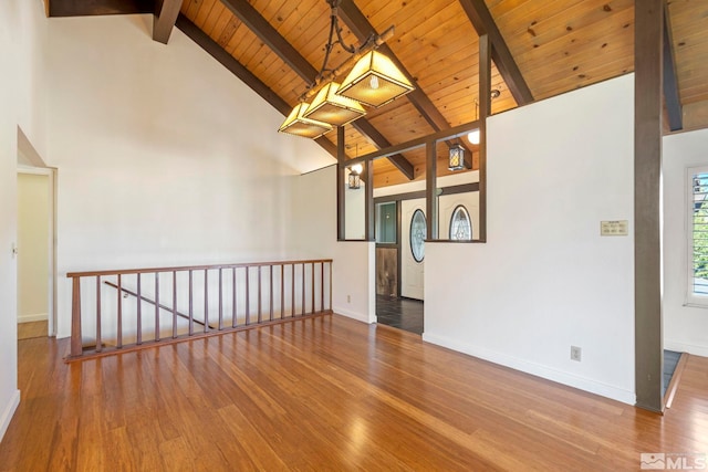 empty room with wooden ceiling, wood-type flooring, beam ceiling, and high vaulted ceiling