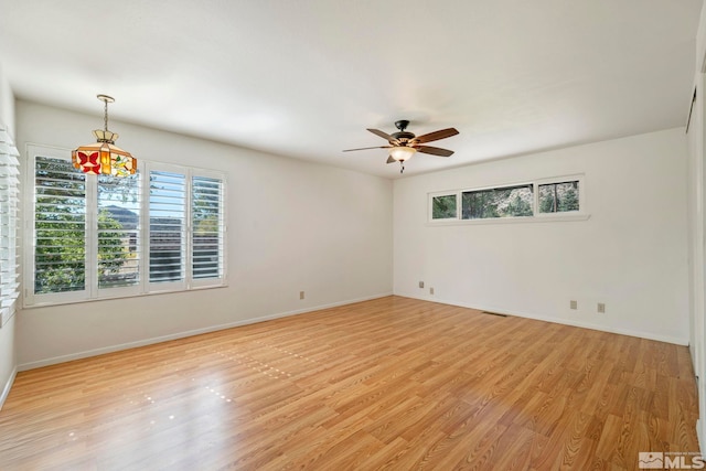 unfurnished room featuring ceiling fan with notable chandelier and light hardwood / wood-style flooring