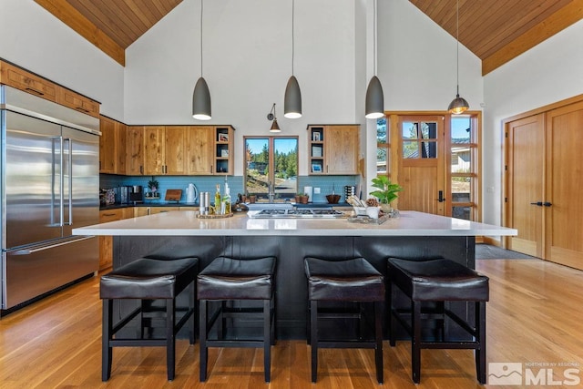 kitchen with appliances with stainless steel finishes, hanging light fixtures, wood ceiling, and high vaulted ceiling