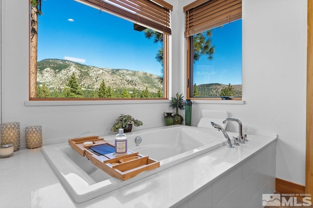 bathroom featuring tiled tub and a mountain view