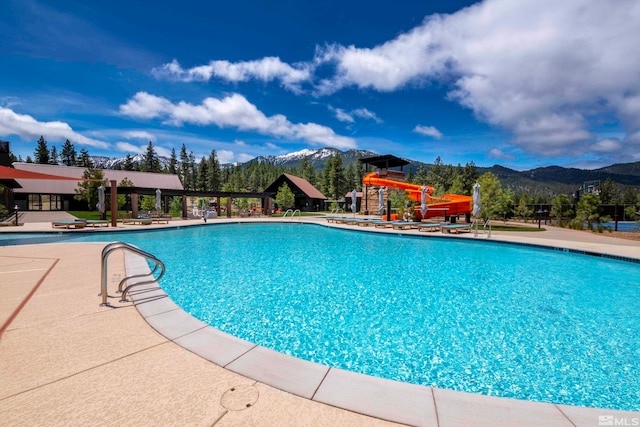 view of pool with a mountain view, a water slide, and a patio area