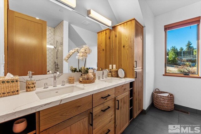 bathroom with walk in shower, vanity, lofted ceiling, and tile patterned flooring