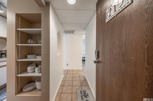 corridor with light tile patterned flooring and a drop ceiling