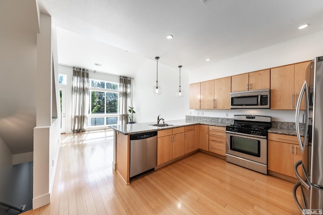 kitchen featuring pendant lighting, sink, kitchen peninsula, light hardwood / wood-style flooring, and stainless steel appliances