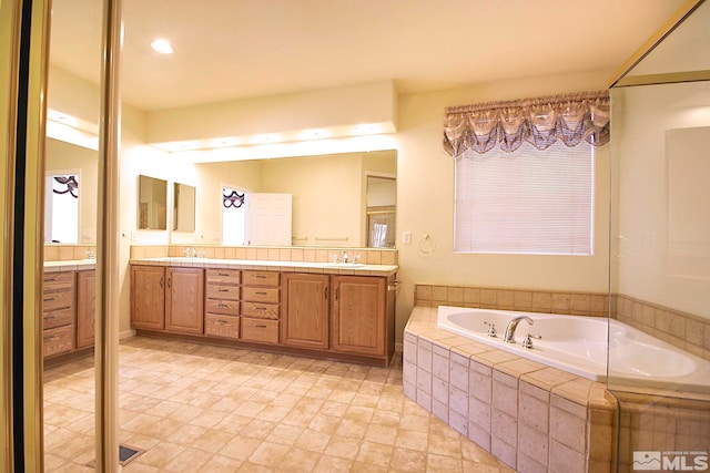 bathroom with vanity and a relaxing tiled tub