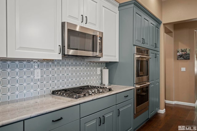 kitchen featuring white cabinets, appliances with stainless steel finishes, dark hardwood / wood-style floors, and decorative backsplash