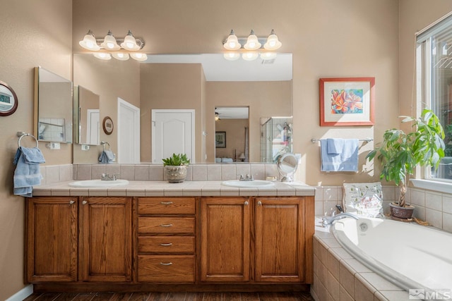 bathroom with vanity, tiled bath, plenty of natural light, and hardwood / wood-style floors