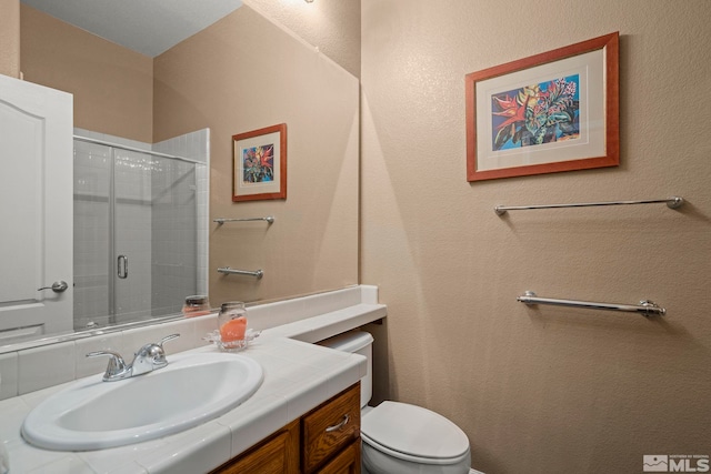 bathroom with an enclosed shower, vanity, and toilet