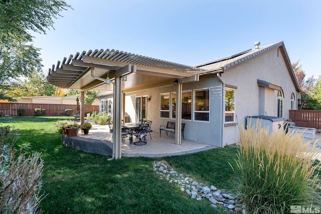 back of house featuring stucco siding, fence, a yard, and a patio