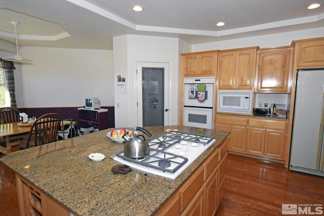 kitchen with light stone countertops, white appliances, and dark hardwood / wood-style flooring