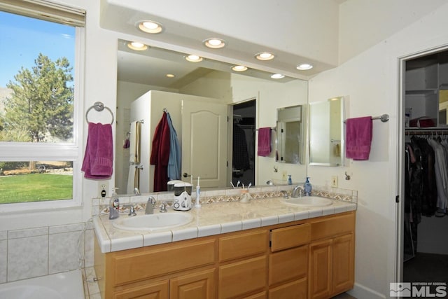 bathroom with a tub, vanity, and tile patterned floors