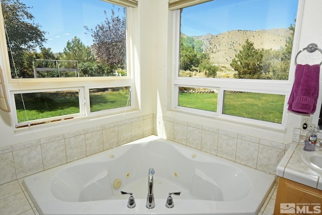 bathroom featuring tiled bath, sink, and a wealth of natural light