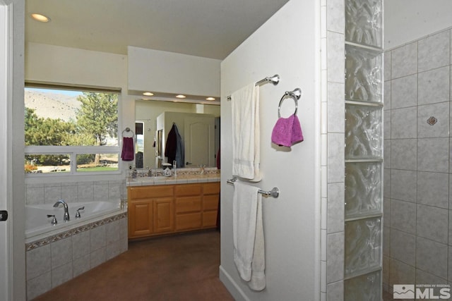 bathroom with vanity and tiled bath