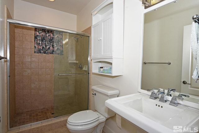 bathroom featuring tile patterned floors, toilet, sink, and a shower with shower door