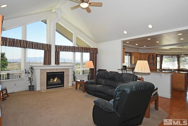 living room featuring beamed ceiling, a fireplace, high vaulted ceiling, carpet, and ceiling fan