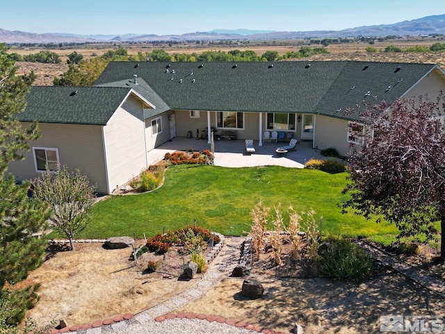 back of house with a lawn, a patio, and a mountain view