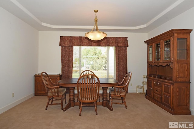 dining room with light colored carpet and a tray ceiling