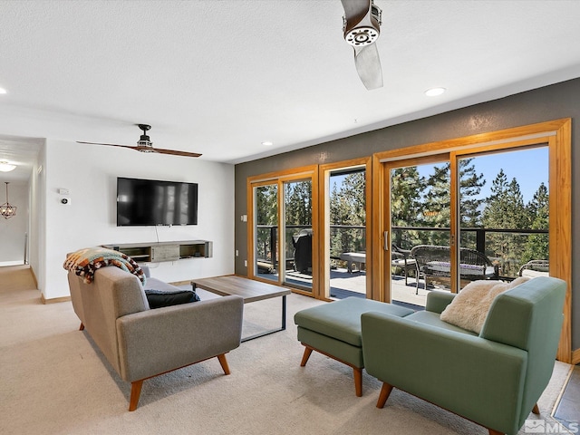 living room with ceiling fan, light colored carpet, and a textured ceiling