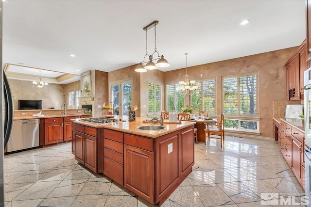 kitchen with appliances with stainless steel finishes, hanging light fixtures, crown molding, a center island with sink, and sink