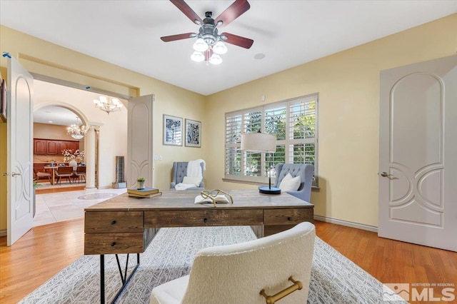 home office with ceiling fan with notable chandelier and light hardwood / wood-style floors