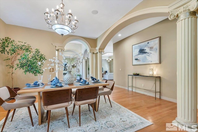 dining room featuring an inviting chandelier, light hardwood / wood-style flooring, and decorative columns