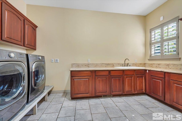 laundry area with cabinets, washer and dryer, and sink