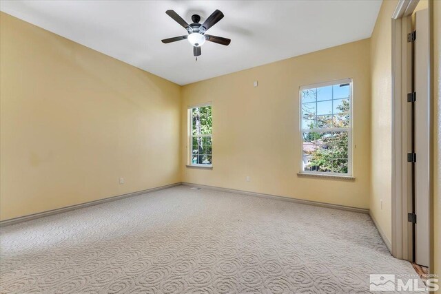 spare room with ceiling fan and light colored carpet