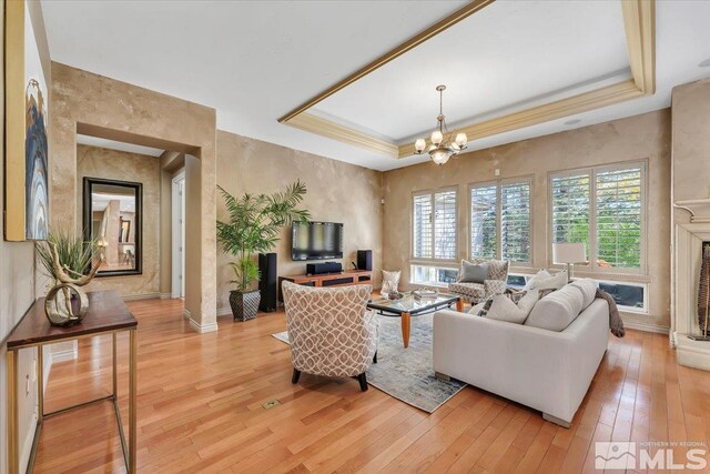 living room featuring light hardwood / wood-style flooring, plenty of natural light, and a tray ceiling